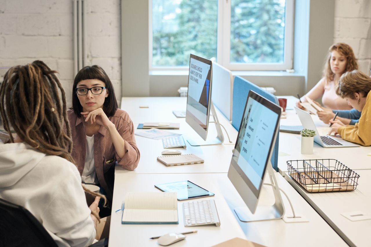 story-01 Diverse group of women working together in a modern office setting, fostering teamwork and creativity.