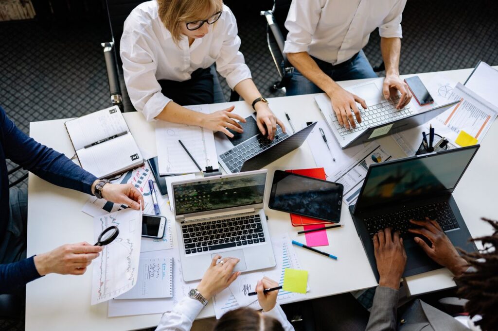 Services Overhead view of a corporate team collaborating with laptops and documents.
